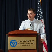 A  man standing at a GVSU podium on stage